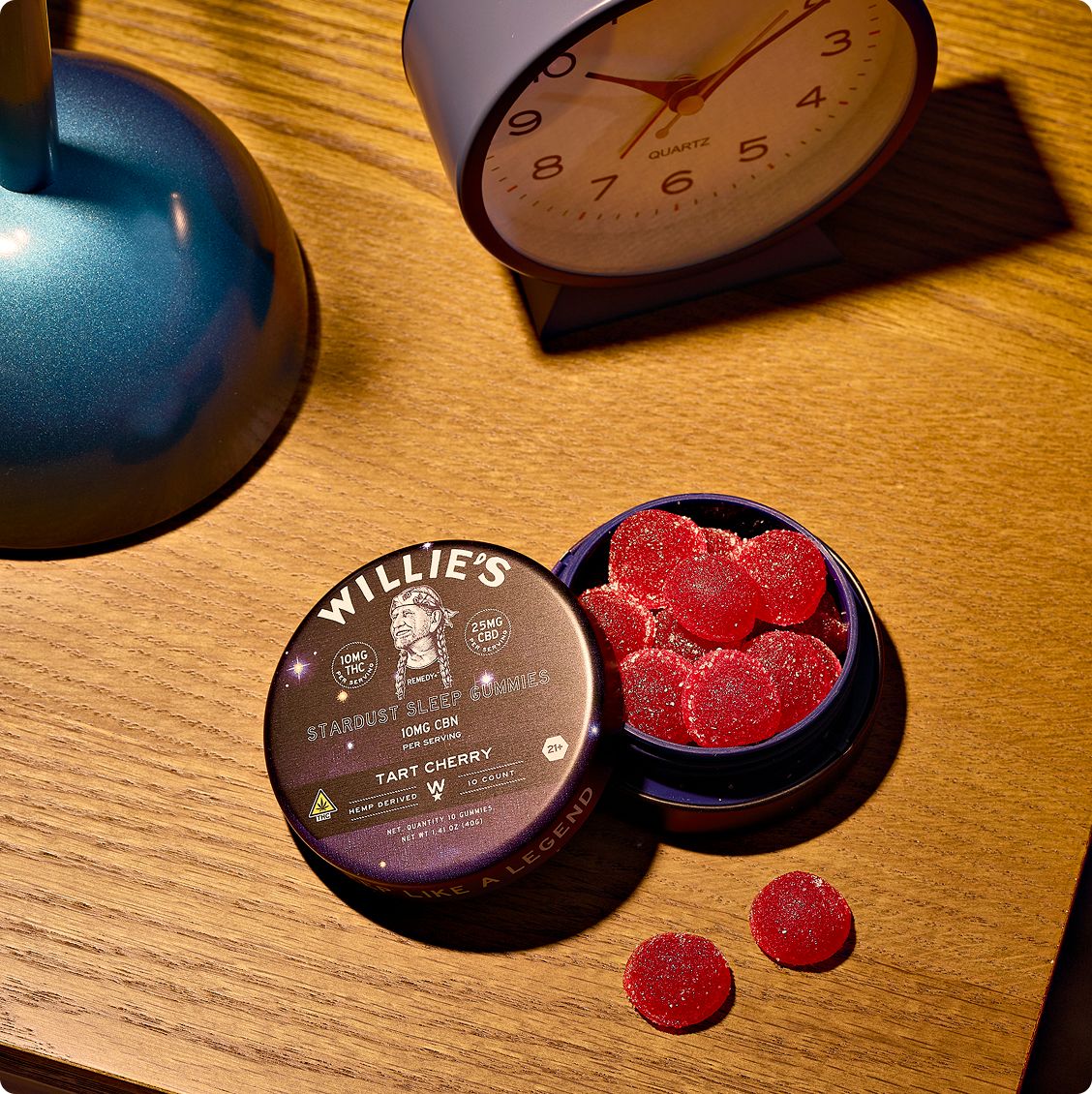 THC gummies side effects guide: a tin of Willie's THC Sleep Gummies on a nightstand beside an alarm clock